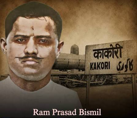 Sepia-toned commemorative illustration combining a portrait of Ram Prasad Bismil with a steam locomotive and a bilingual Kakori railway station signboard reading काकोरी and KAKORI.